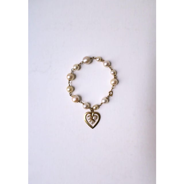 A beautiful freshwater pearl and cultured pearl 14kt yellow gold heart charm bracelet, circa mid to late-20th century....