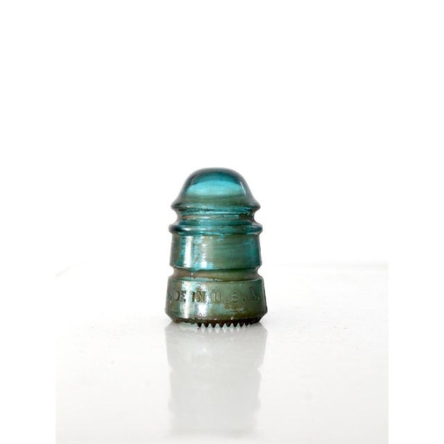 This antique Hemingray No. 12 telephone insulator is crafted from luminous aqua glass with embossed lettering and a...