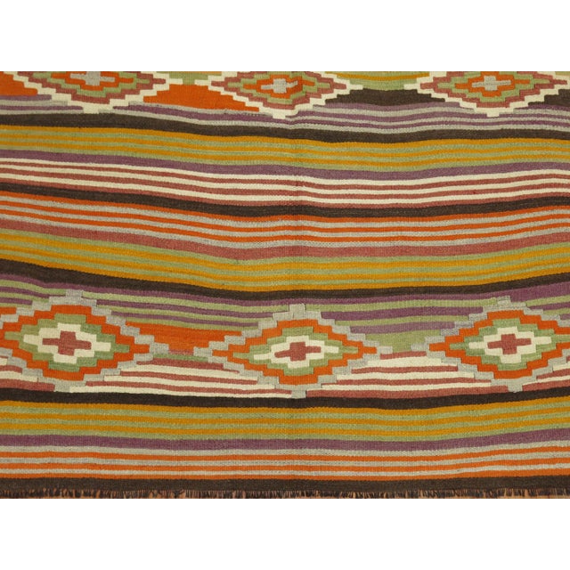 An intermediate size vintage Turkish Kilim with a colorful striped design throughout.
