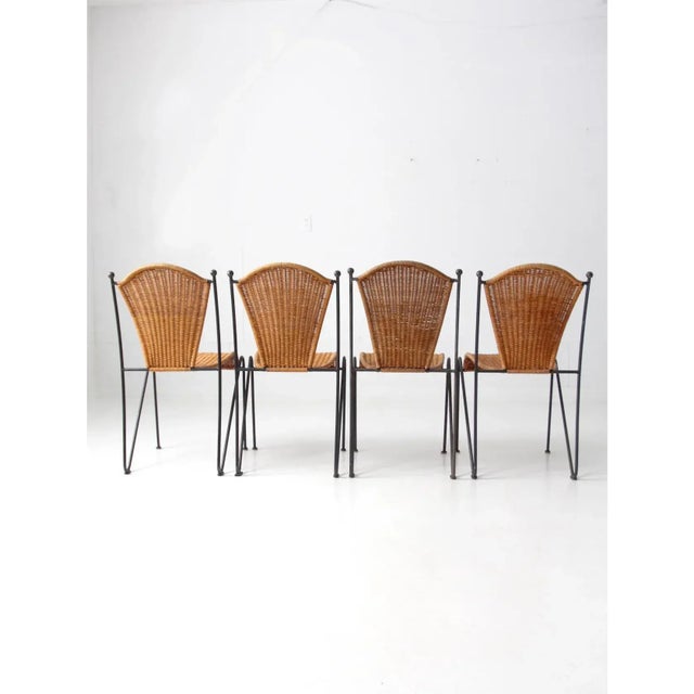 This is a set of four mid century wicker and wrought iron dining chairs in the style of Frederic Weinberg, circa 1960s A...
