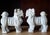 A striking pair of mid-century modern "Blanc de Chine" white porcelain standing guardian lion (Foo Dog) statues. Crafted...