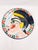 Bring a bold, artistic statement to your walls or tablescape with this striking terracotta glazed plate. Featuring a hand-...