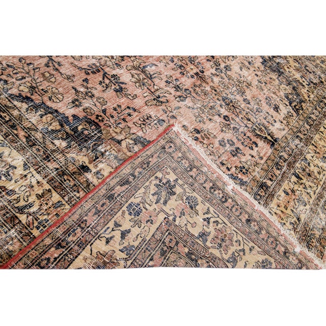 Beautiful vintage Persian distressed hand-knotted wool rug with a peach field. This piece has a beige frame and multicolor...