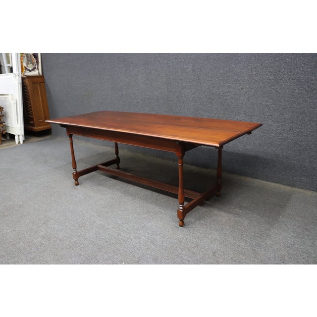 Antique walnut harvest table featuring a two-board top with a rich, warm brown finish and a simple molded edge. The...