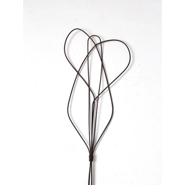 This is an antique rug beater. The carpet beater has a honey-comb twisted design with wooden handle with metal loop hang.