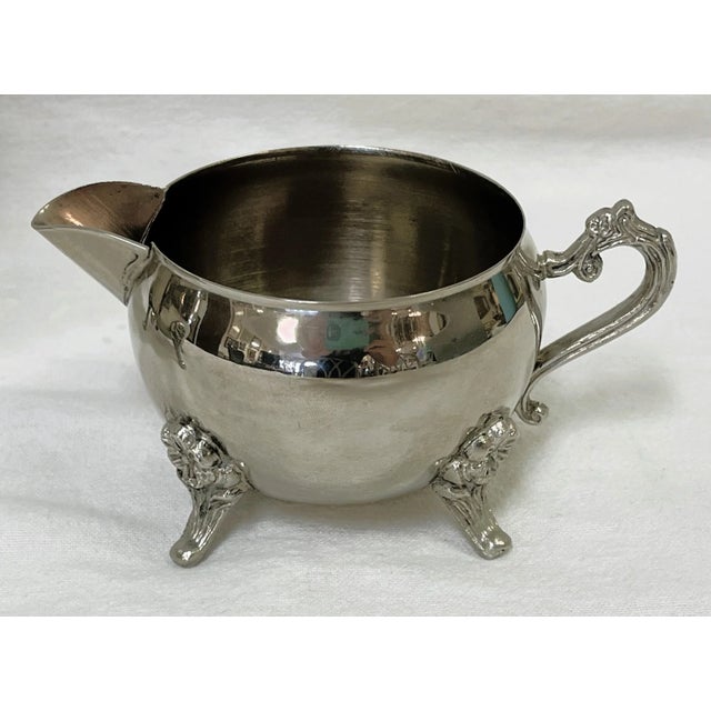 Pretty vintage three piece tea service. The elegant set has a floral design with scrolled handles, and pedestal feet. The...