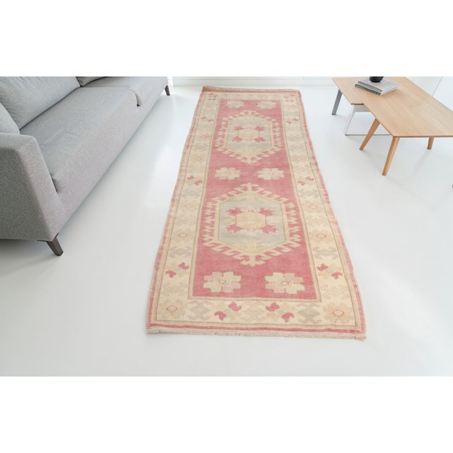 This is a vintage Turkish Oushak rug from the Mid 20th Century. The piece was hand-knotted.