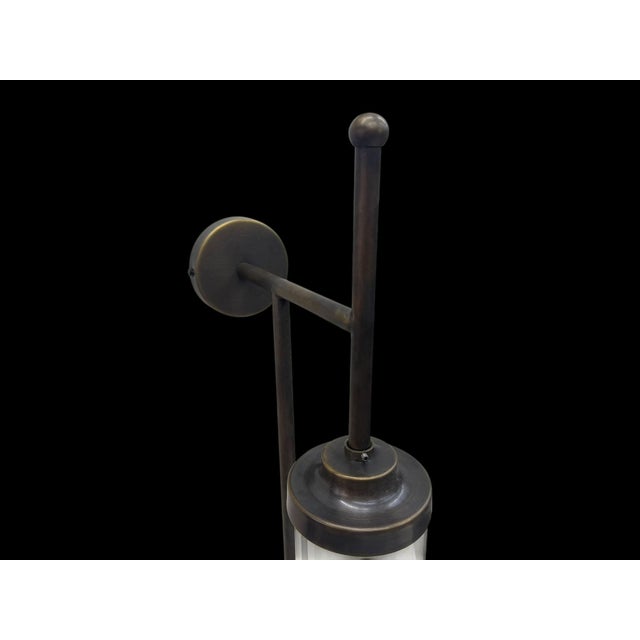 A handmade brass light fixture with a clear cylindrical glass tube and a clean linear frame. Designed as a decorative wall...