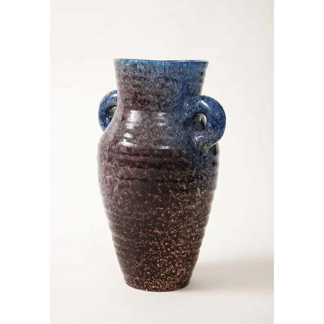 A ceramic jug with handles in a stunning glaze of aubergine and blue produced by Accolay Pottery. Founded in the 1950s in...