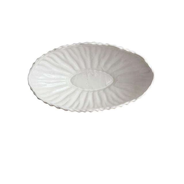 A well-sized ceramic white planter in a satin finish. Organic oval design with a scalloped rim. Its exterior features...