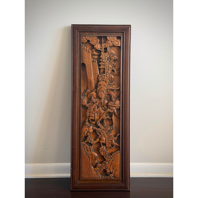 A striking large-scale hand-carved Chinese teak wall panel featuring an elaborate historical battle scene rendered in...