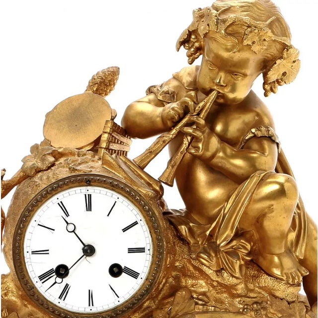 A rocaille mantel clock made of gilded bronze on a fireplace. It depicts putti in the image of dionysus playing the flute....