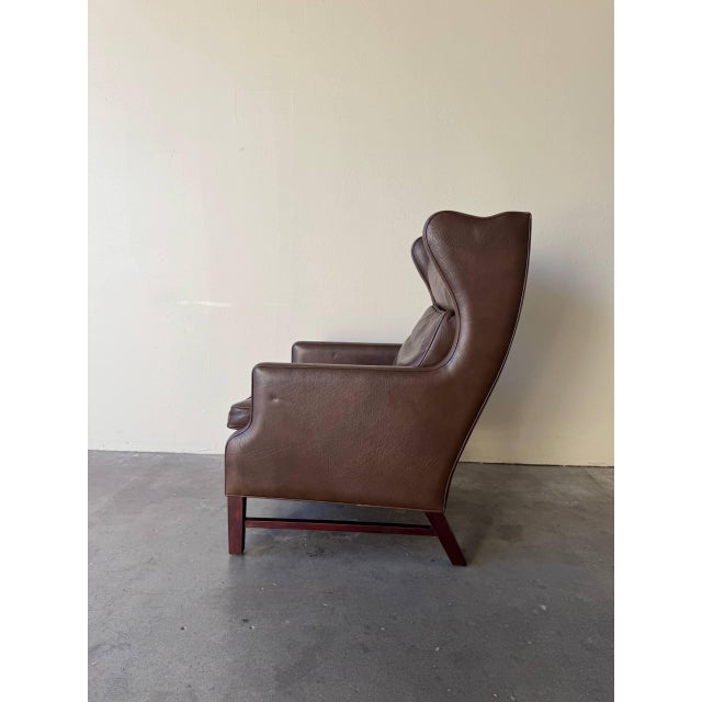 Elegant mid-century Danish wingback lounge chair, crafted in the 1960s and executed in richly patinated brown leather,...