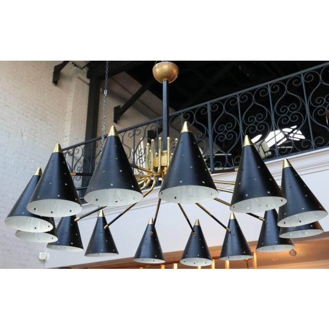 Midcentury style brass chandelier with 14 black perforated shades. Available Now