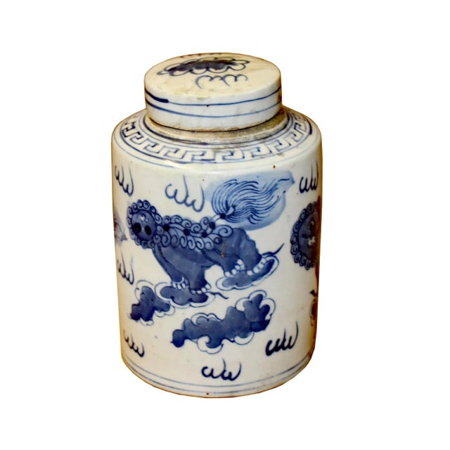This is a handmade ceramic container urn jar in the off white base color. The surface has a blue color Foo Dogs lions...