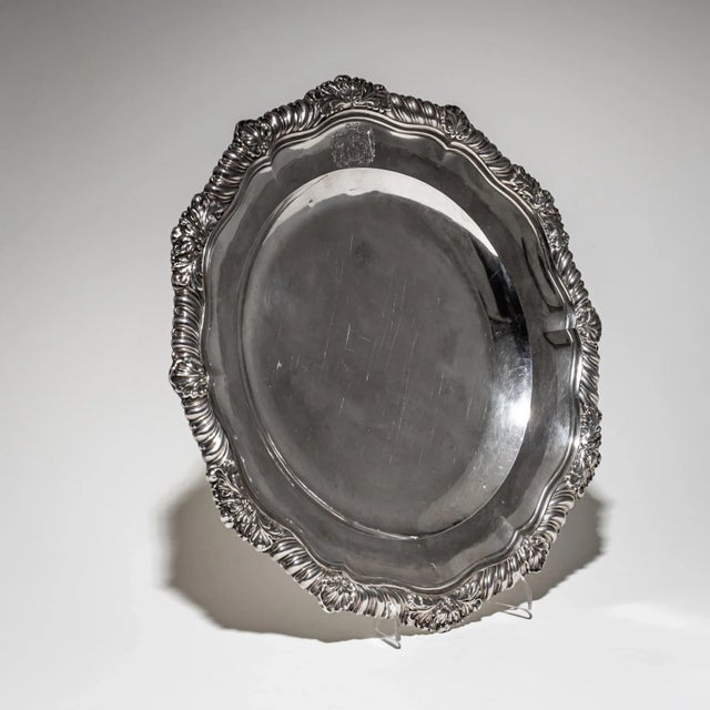 Elegant silver plate featuring a smooth well, scalloped and gadrooned rim adorned with shell and leaf motifs. The engraved...
