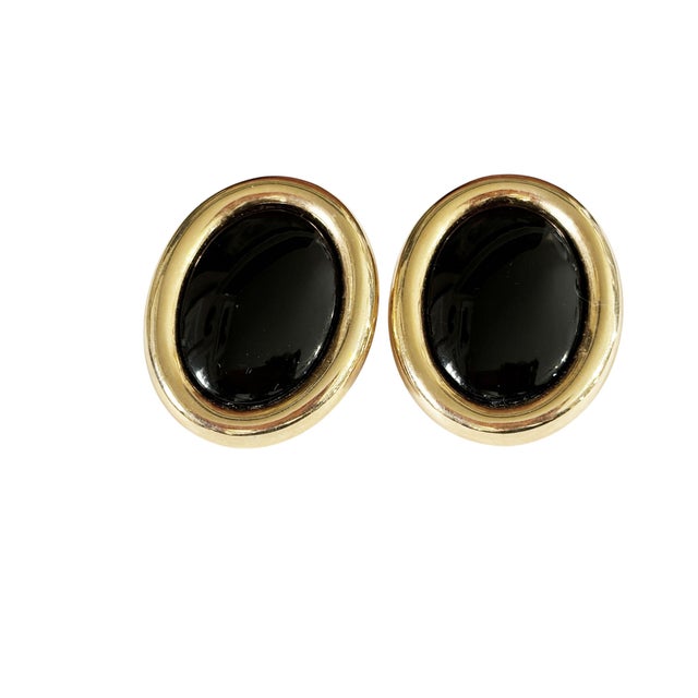 A striking pair of vintage modernist clip-on earrings featuring polished gold tone metal paired with bold black enamel...