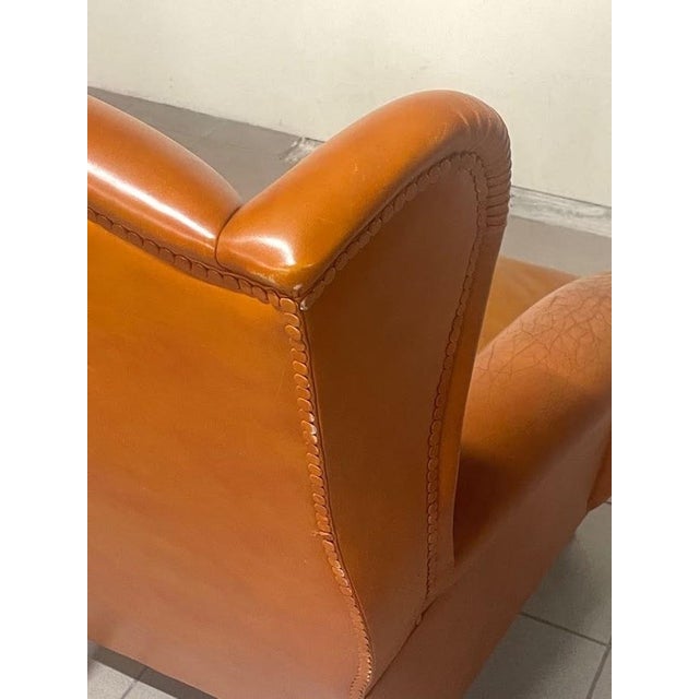 Large Poltrona Frau armchair in cognac leather from the 1960s with ebonized wooden feet and the original plaque. The...