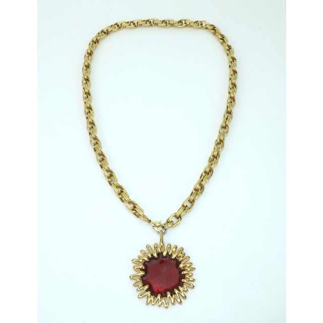 C.1970 Jomaz gold plated sunburst pendant necklace consisting of a red enameled pendant attached to a fluted chain link...
