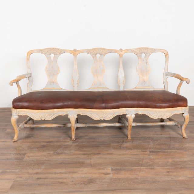 Early 19th century Swedish rococo bench settee crafted in pine. Graceful curves accent the arms, feet, and back, giving...