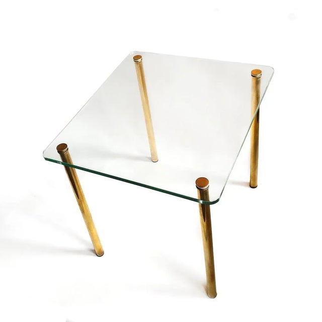 - Small Mid-century Italian occasional table - Minimalist design - With brass legs attached to a glass top - The legs...