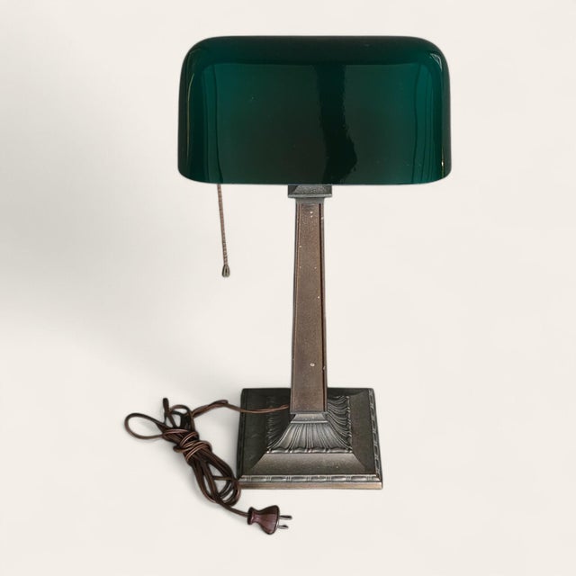 An early 20th century American Emeralite desk lamp with a green to opaque white cased glass shade, raised on a single-arm...