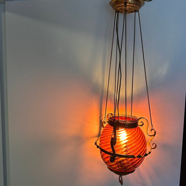 Beautiful antique Victorian hanging oil lamp featuring a stunning ruby swirl art glass font housed in an ornate brass...