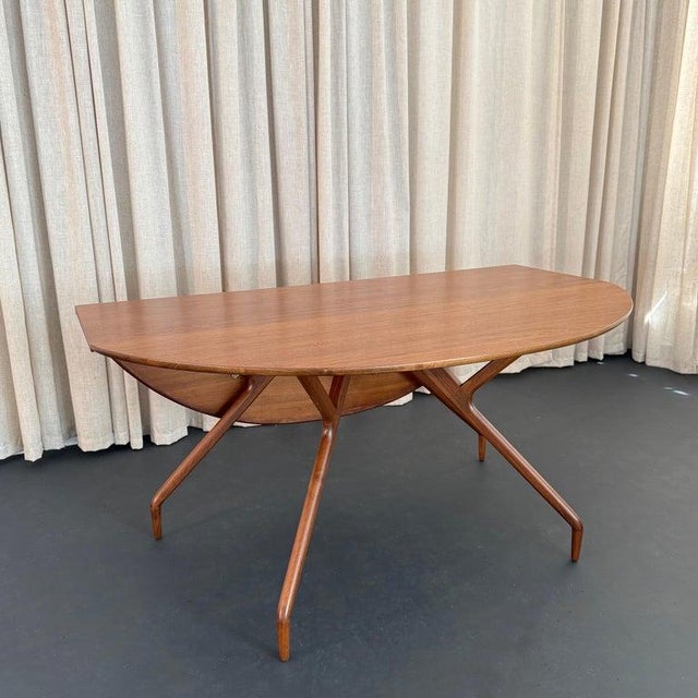 This iconic Mid-Century Modern walnut drop-leaf dining table with spider leg design was created by the Swedish-American...