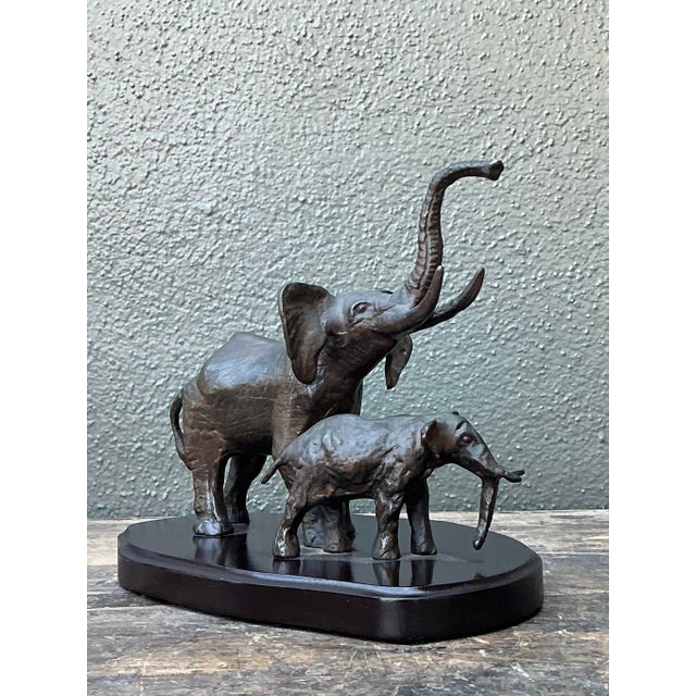 This evocative bronze sculpture captures a tender and majestic moment between a mother elephant and her calf, rendered...