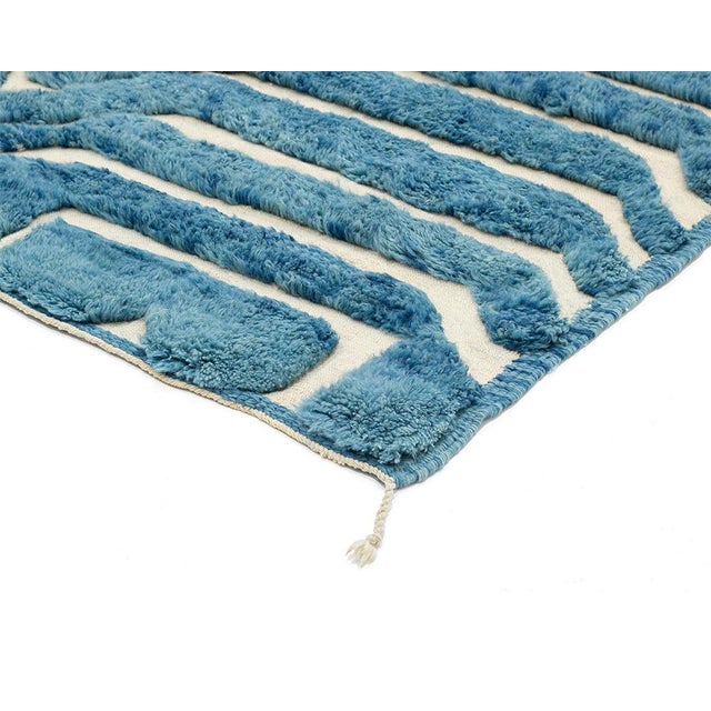 Rhythm woven into every line. Rows of soft chevron stripes ripple across this rug in deep Aegean blue, each band separated...