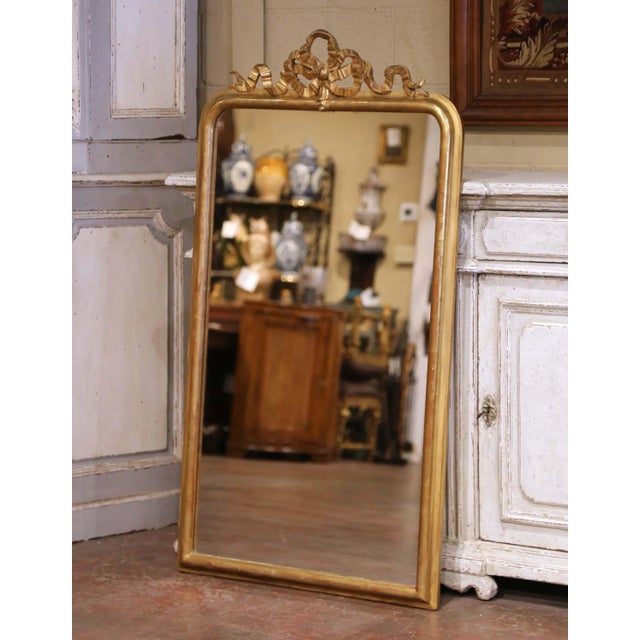 This elegant antique wall mirror captures the refined symmetry and decorative restraint of the Louis XVI style. Crafted in...