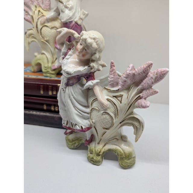 Delightful pair of hand-painted porcelain spill vases featuring a young boy and girl posed against stylized foliage with...