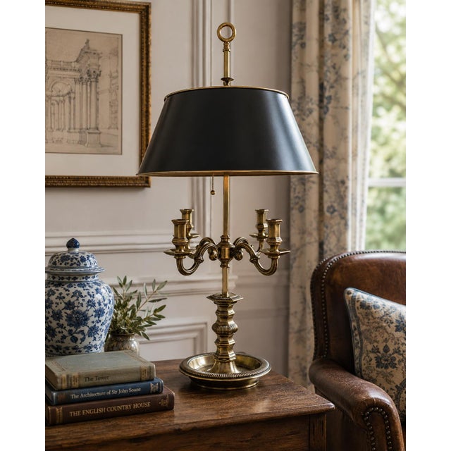 A classic bouillotte lamp rendered in warm brass, distinguished by its sculptural four-arm base and clean, tailored black...