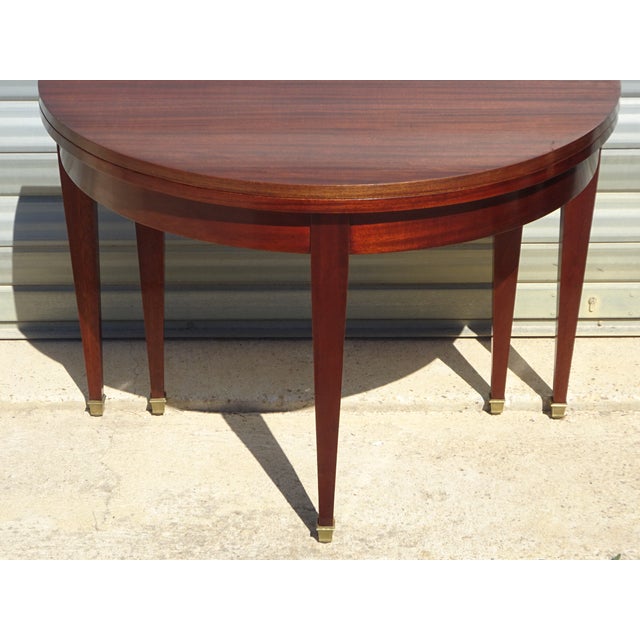 Beautiful Empire-style mahogany half-moon console table with six square, tapered legs mounted on gilt brass feet. This...