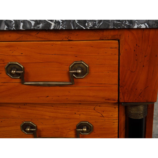 A French Empire style walnut commode from the early 20th century, with grey veined marble top four drawers and black...