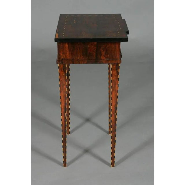 Occasional table in Classicist style. Palisander on pinewood, framed fields of marquetry from band Intarsia. (G-Sam-20)....