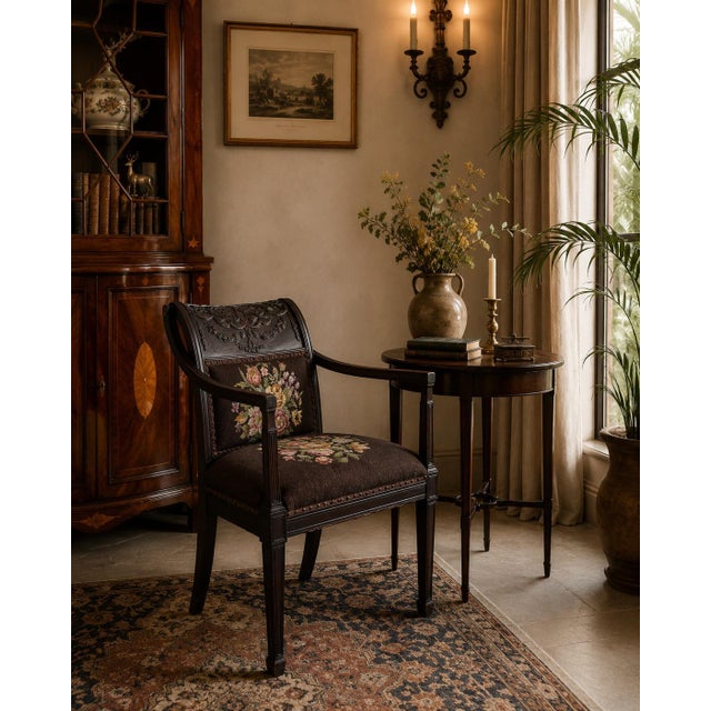 Elegant antique French Neoclassical-style armchair crafted from dark mahogany, featuring a beautifully carved crest with...