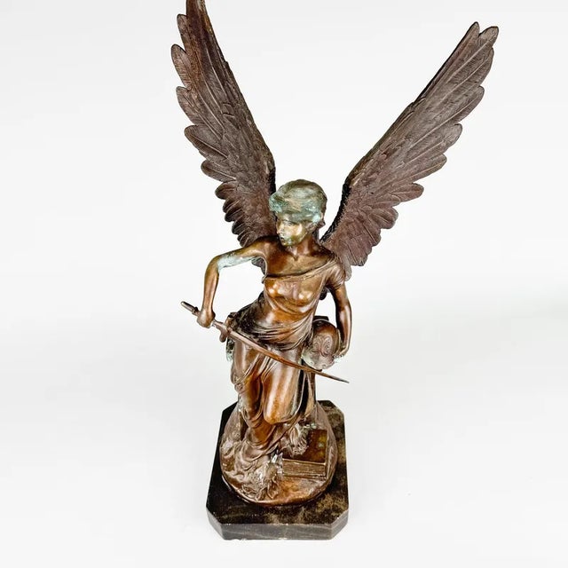 Tall bronze sculpture of an angel with sword on marble, original patina.