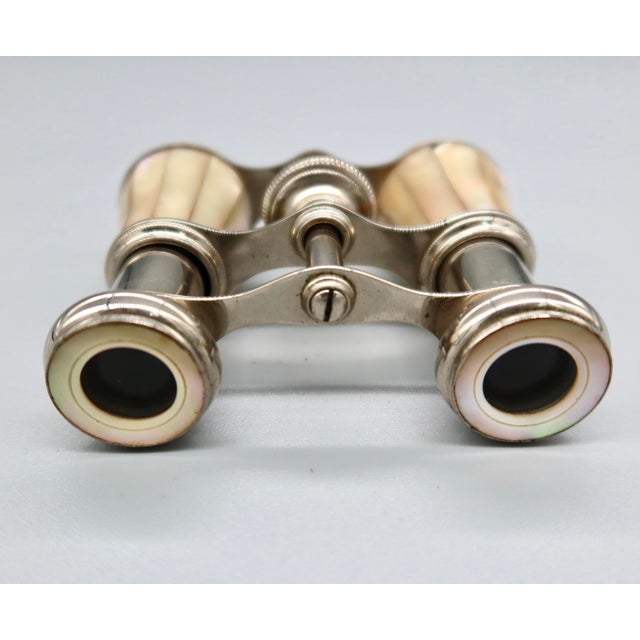 A charming pair of antique opera glasses with fluted mother-of-pearl barrels and silver-tone metal fittings, featuring a...