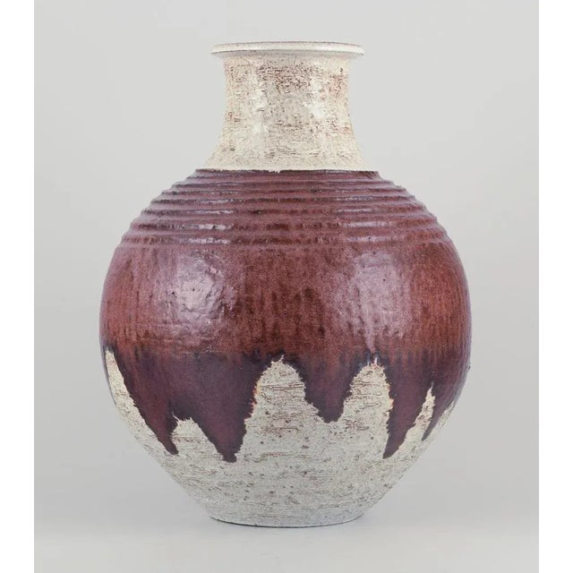 European studio ceramicist. Unique floor vase in ceramic. Flowing glaze in brown hues on a sand-colored base. Hand-glazed....