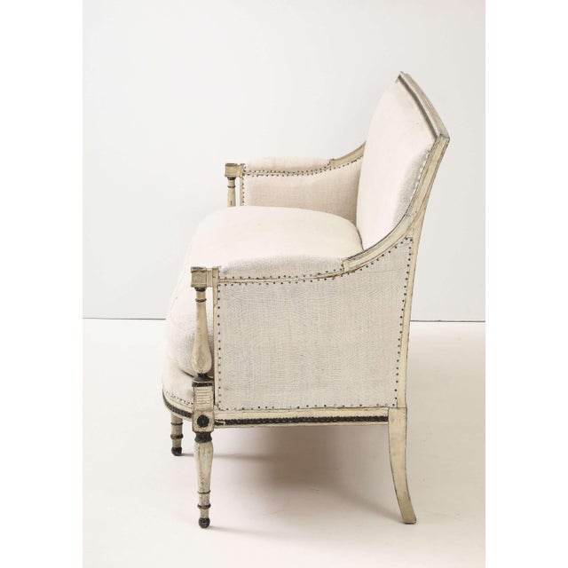 An elegant French settee retaining its original pale white with black accents painted finish and bronze nail-head trim....