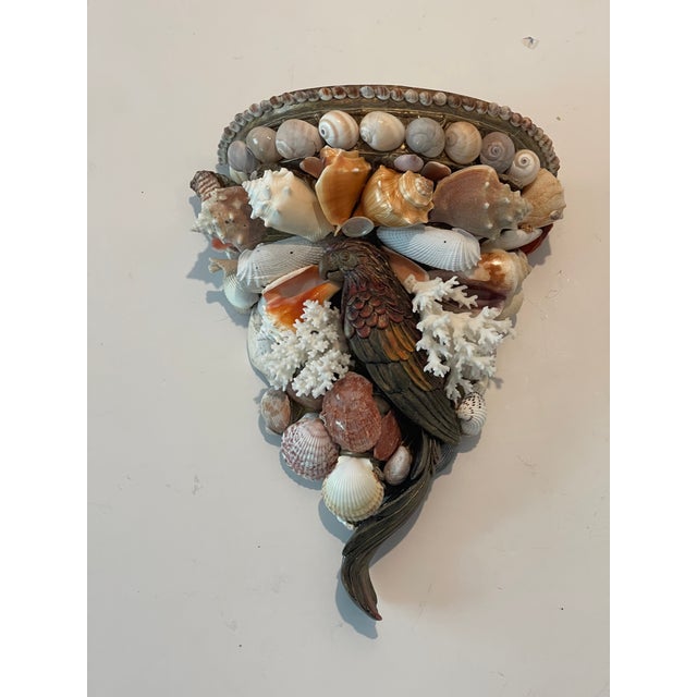 Richly encrusted with selective sea shells and white birds nest coral branches, wall bracket with parrot figure in the...