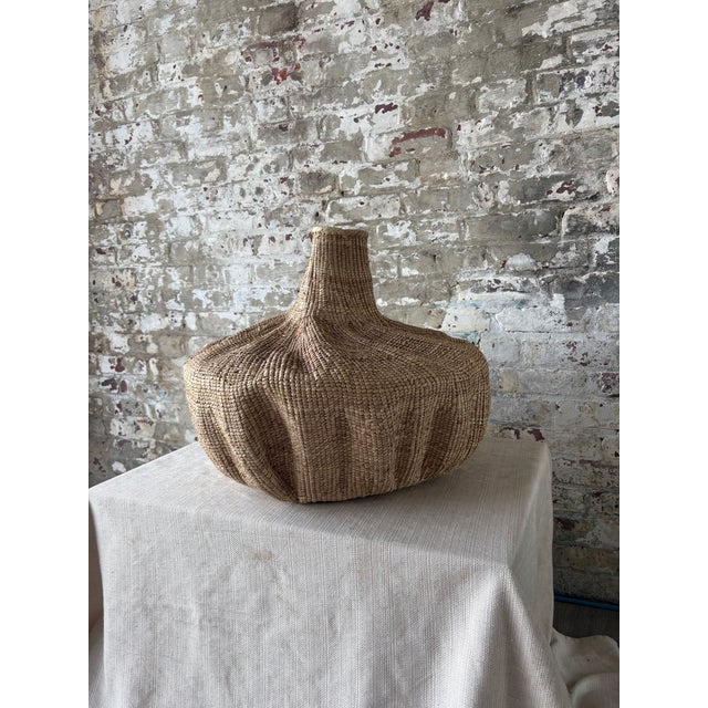 A striking oversized woven vessel with bold sculptural form and rich organic texture. Crafted in natural fibers, this...