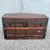 A striking late 19th-century wooden steamer trunk featuring a gently curved barrel top, dark iron banding, decorative...