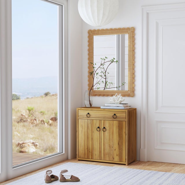 The Butler Specialty Company Flora Wall Mirror exudes casual elegance with its handwoven rattan frame and scalloped edges...
