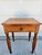 A classic antique primitive side table with one drawer and turned legs. This piece is in good antique condition with age-...