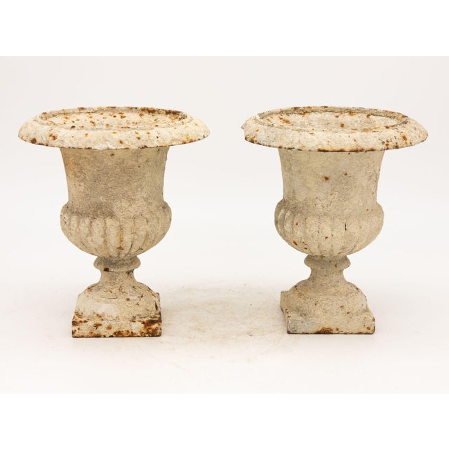 These white-painted cast iron urns are a beautiful example of French design. They have a timeless quality that makes them...
