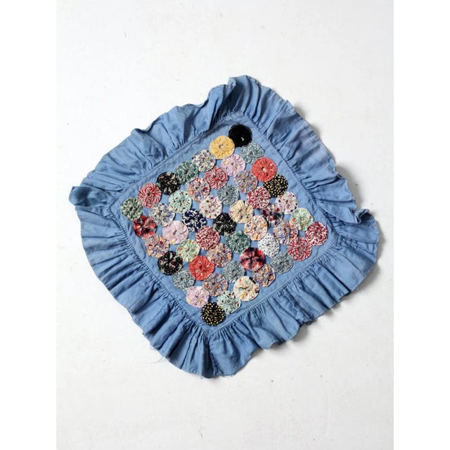 Vintage yo-yo quilted pillow cover featuring colorful floral fabric yo-yos arranged on a blue cotton ground with a large...