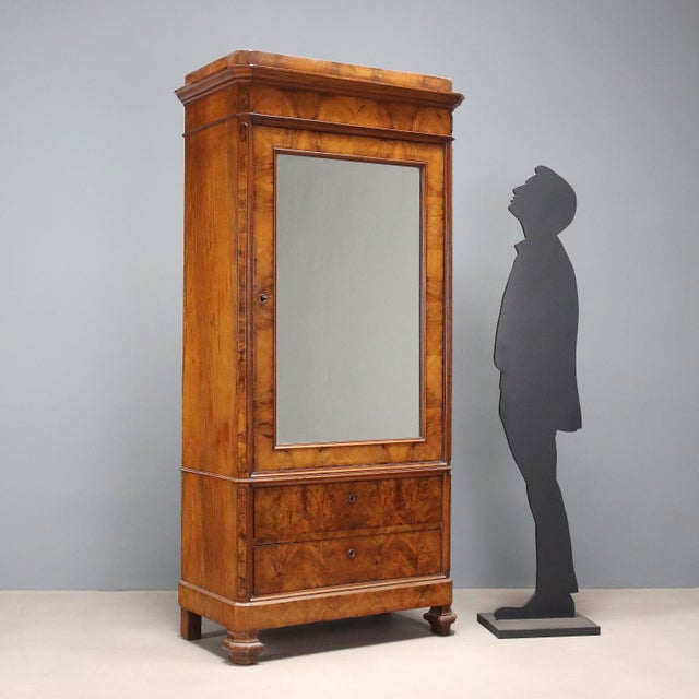 Umbertino wardrobe veneered in walnut. Front door with mercury mirror and two drawers, 45° uprights and legs, the former...