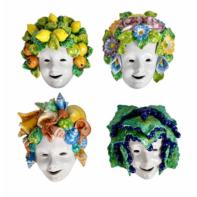 This is a set of four vintage Italian glazed ceramic wall masks, each featuring a smiling white face framed by an...